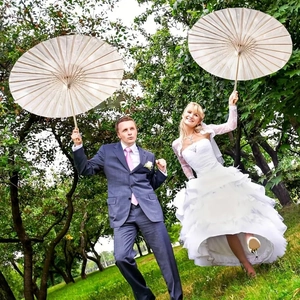 Outdoor wedding detail featuring white layered bridal gown and decorative beige paper umbrellas