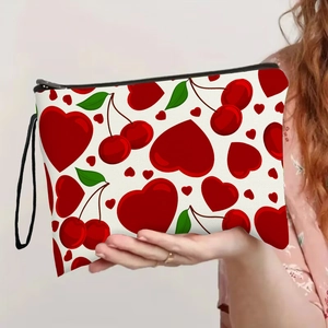 Portable makeup bag with red heart and cherry prints, featuring a black wristlet and zipper