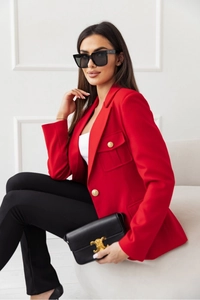 Dettaglio blazer rosso con bottoni dorati in rilievo e design a vita sfiancata