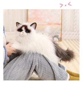 Close-up of realistic ragdoll cat plush held on lap showing soft fur and blue eyes