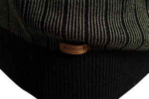 Close-up of vertical striped knit fabric and brown leather brand patch on the sweater hem