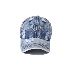 Detail of distressed vintage blue washed denim baseball cap with heavy ripped hole effects