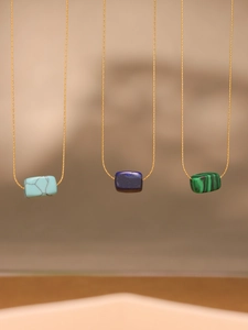 Close-up of lapis lazuli and malachite rectangular stone pendants on 18k gold chain
