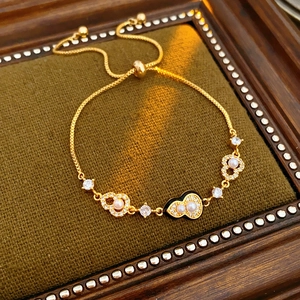 Detail of adjustable gold-plated heart bracelet with pearls on green velvet tray
