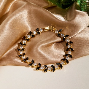 Detailed shot of a gold bracelet with black marquise gems and white zircons on silk