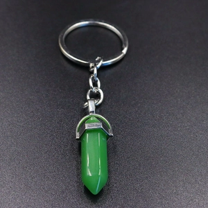 Detail shot of a green hexagonal crystal bullet pendant on a silver keychain ring