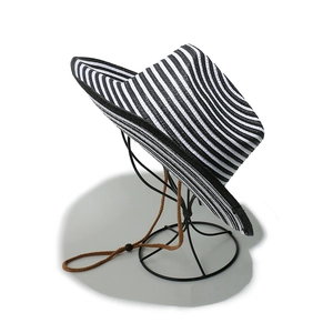 Close-up of black and white striped straw sun hat with adjustable brown chin strap