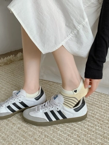 Close-up of beige striped low-cut socks featuring a black heart patch on the heel