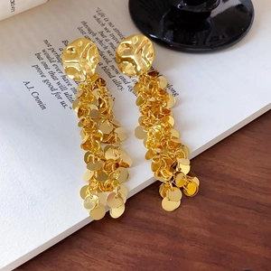 Vintage Goldene Pailletten Quastenohrringe mit Pfeil-Dreieck-Kette auf Buchhintergrund