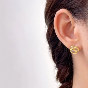 Close-up of geometric gold-plated earrings with clear zircons on model's ear