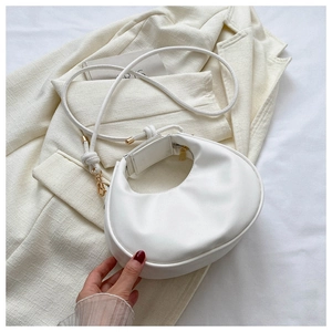Detailed macro view of white crescent moon handbag with gold hardware and matte leather