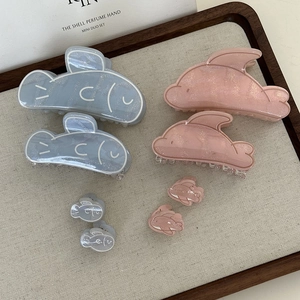 Detail showing blue and pink shark hair clips in different sizes on a fabric tray