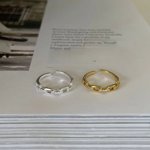 Dettaglio di anelli a catena oro e argento con zirconi su pagine di libri eleganti