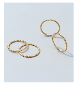 Close-up of four minimalist golden beaded rings in 18k gold-plated titanium steel