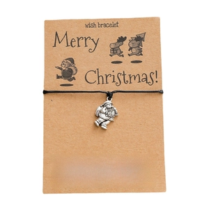 Detailed view of handmade woven Santa Claus charm bracelet on a Merry Christmas kraft card