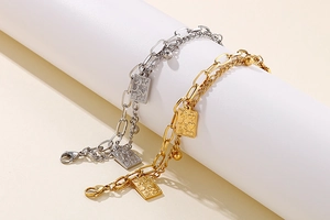 Detail of gold and silver double-layered chain bracelets with square poker card pendants