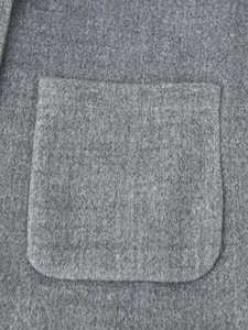 Close-up of a square patch pocket on a grey wool coat showing high-quality stitching
