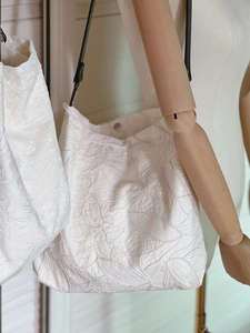 Close-up of floral embroidery on a beige cotton tote bag with a magnetic buckle