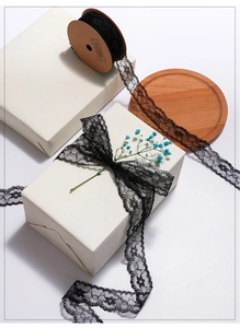 Detailed view of black floral lace ribbon on wooden tray for gift wrapping and DIY