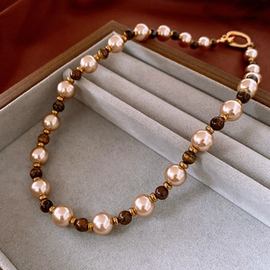 Vue détaillée du collier de perles champagne et pierre œil de tigre dans son écrin