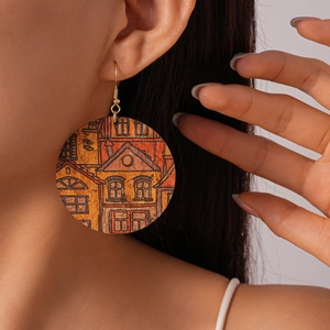 Close-up of bohemian leather earrings with architectural print and gold ear hooks