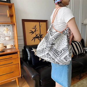 Detail of floral paisley tote bag with orange checkered strap shown on a model