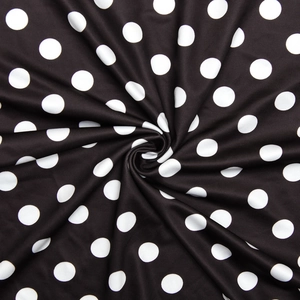 Close-up of smooth black fabric with white polka dots arranged in a spiral