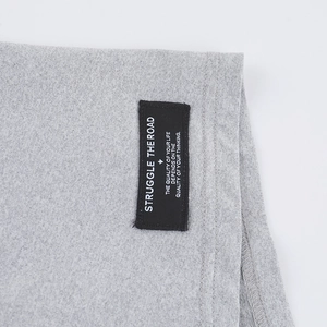Détail du tissu en maille grise avec étiquette tissée noire et coutures soignées