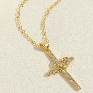 Detailed macro view of 14K gold-plated cross pendant with heart motifs and sparkling zircons