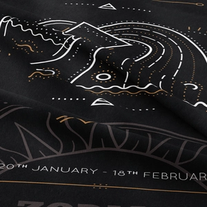 Detail shot of the woven fabric texture with Aquarius zodiac print on a black tapestry