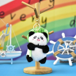 Detail view of a cute plush panda keychain hanging on a wooden jewelry display stand