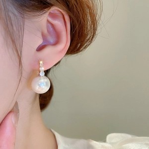 Gros plan de boucles d'oreilles perles élégantes avec zircons portées par un mannequin