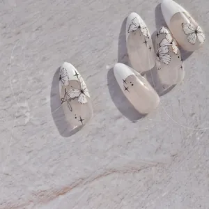 Gros plan d'ongles amande avec motifs de papillons noirs et détails de petites étoiles