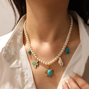Detail of pearl necklace with turquoise turtle, fish, coral and conch charms