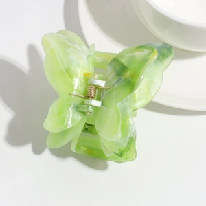 Close-up of light green acetate butterfly hair claw clip with marble texture and gold spring