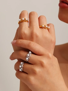 Macro shot of layered gold and silver rings featuring elegant pearls on model hands