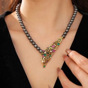 Détail de collier vintage en perles noires avec pendentif fleur dorée et gemmes