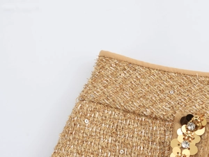 Macro shot of gold tweed fabric with shimmering sequins and rhinestone accents