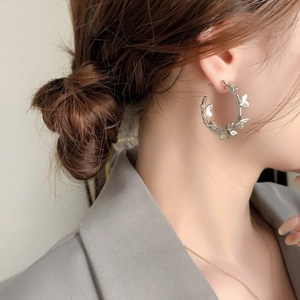 Silver butterfly hoop earring shown on model with intricate hollow-out metal details
