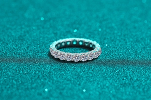 Macro shot of silver eternity ring with pavé moissanite on a glittering blue background