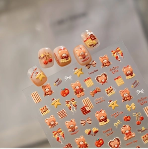Close-up of 3D bear nail stickers with stars and bows on creamy orange fake nails