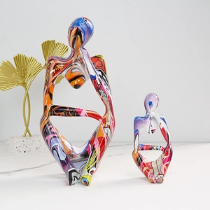 Modern resin thinker sculptures with colorful graffiti finish on white marble surface