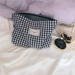 Detail of black and white checkered canvas makeup bag with Time To Party label and zipper
