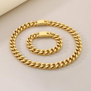 Gros plan d'un ensemble collier et bracelet gourmette dorée de 13mm en acier titane poli