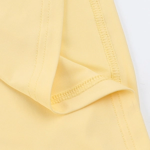 Macro shot of double-needle hem stitching and fine knit texture on yellow dress
