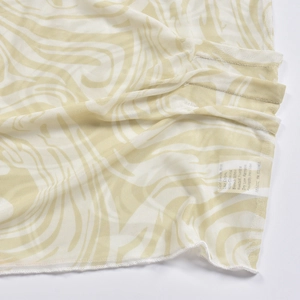Close-up of beige mesh fabric with abstract ripple pattern and internal care label