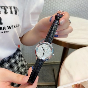 Detail showing crystal dial, silver case and black leather strap on female wrist
