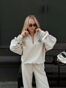 Detail of the royal members club logo printed on the cream white half-zip sweatshirt