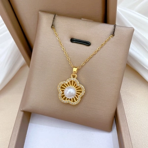 Detail of gold floral necklace with a white pearl and zircon accents in a gift box