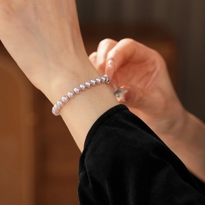 Close-up of elegant silver grey pearl beaded bracelet on a woman wrist in soft light